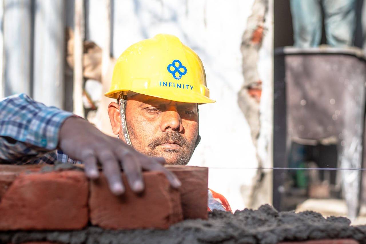journey A construction worker carefully aligning bricks on a wall in Delhi, India.
